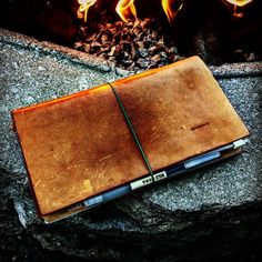 two notebooks sitting on top of each other in front of a fire pit with flames