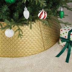 a christmas tree with ornaments in a basket on the floor next to a present box