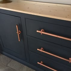 a black dresser with copper handles and knobs