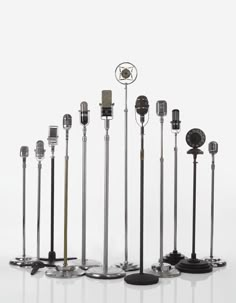 an assortment of microphones and stands on a white surface with reflections in the background