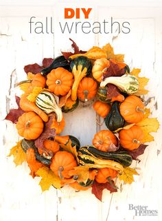 a wreath made out of pumpkins and gourds on a white wooden background