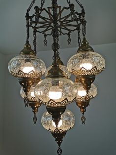 a chandelier with five lights hanging from it's center and four glass globes on the bottom