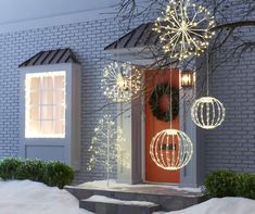 a red door is decorated with christmas lights and ornaments in front of a brick house