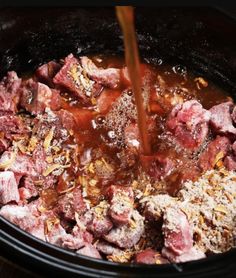 the meat is being poured into the slow cooker to make it easier to cook