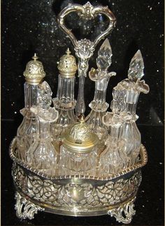 an ornate glass and metal tray with various items in it on a black table top