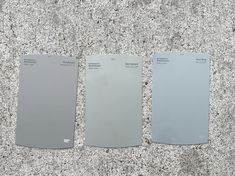 three different shades of gray paint sitting on top of a floor next to each other