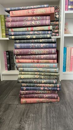 a stack of books sitting on top of a wooden floor next to a book shelf