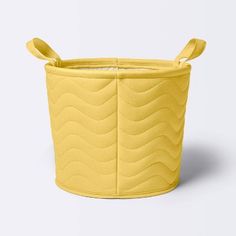 a small yellow basket with handles on the top and bottom, sitting in front of a white background