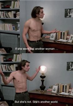 a shirtless man standing in front of a desk next to a bookshelf