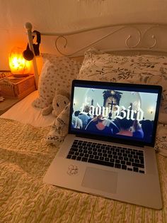 an open laptop computer sitting on top of a bed next to pillows and stuffed animals