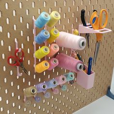 several spools of thread are hanging on a pegboard