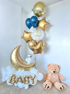 a teddy bear sitting next to balloons that say baby on the moon and balloon letters