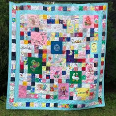 a patchwork quilt hanging on a clothesline in front of some trees and bushes