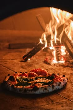 a pizza sitting in front of an open fire