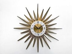 a clock that is on the side of a wall with gold and white numbers in it