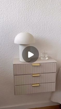 a white dresser sitting next to a wall with a glass jar on top of it