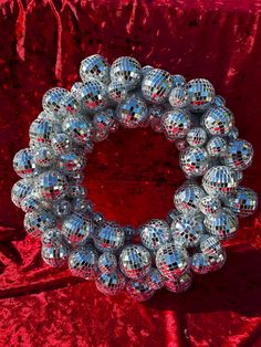 a bunch of shiny silver balls sitting on top of a red velvet covered table cloth