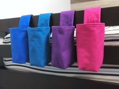 four different colored bags hanging on the side of a bed