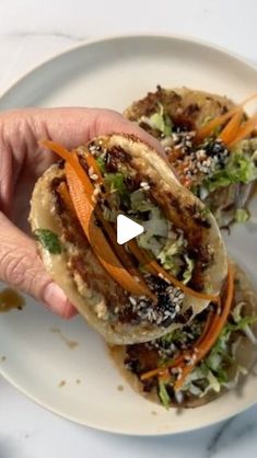 a person is holding up a taco on a plate with shredded carrots and lettuce