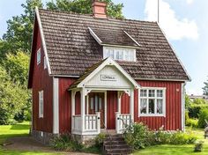 a red and white house sitting on top of a lush green field