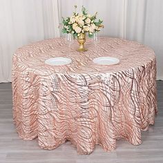 a table with two white bowls on top of it next to a vase filled with flowers