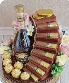 there is a cake that has chocolates on it and a bottle of wine in the middle