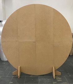 a large round wooden object sitting on top of a floor next to a white wall