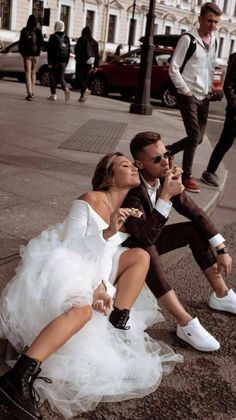 a man and woman sitting on the ground eating ice - creams while wearing tuxedos