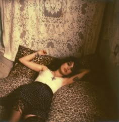 a woman laying on top of a leopard print bed