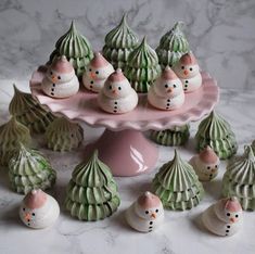 there are many small snowmen sitting on the cake platter with little shells around them