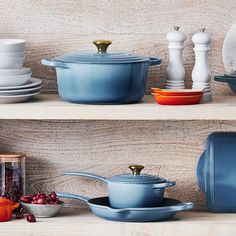 pots and pans sit on shelves with dishes in front of them, along with utensils