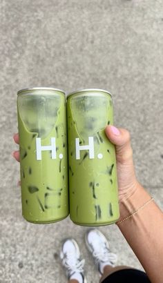 two people holding up green cups with the word h on them