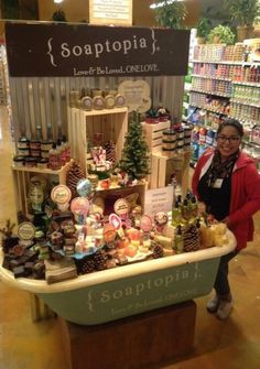 a woman standing in front of a counter filled with soaps