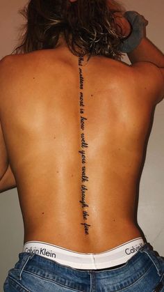 the back of a woman's lower back tattoo with words written on it and in cursive writing