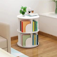 a white table with books on it and a plant in the corner next to it