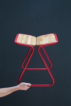 a person holding up a red chair with a book on it's back legs