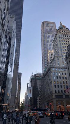 many people are crossing the street in front of tall buildings on a busy city street