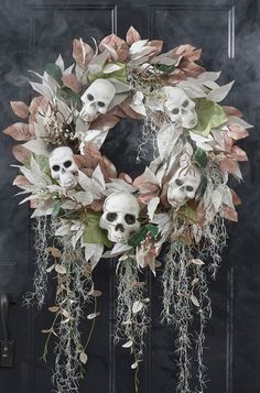 a wreath with skulls and flowers hanging from it's sides on a black door