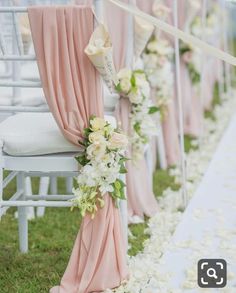 rows of white chairs with pink sashes and flowers lining the aisle at a wedding