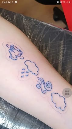 a person with a tattoo on their leg that has clouds and rain coming out of it