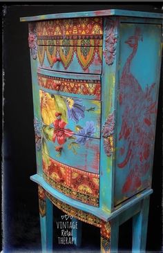 an old dresser painted with colorful designs on the top and bottom, sitting in front of a black background