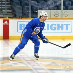 a man in blue uniform playing hockey on an ice rink