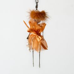 an orange necklace with feathers and pearls hanging from it's back end on a chain