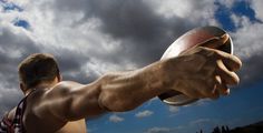 a man holding a frisbee in his right hand under a cloudy blue sky