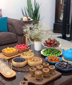 a table filled with bowls and trays of fruit on top of a coffee table