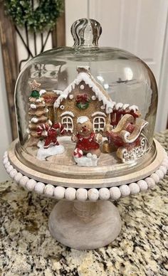 a glass clochel with gingerbread house under it