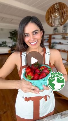 a woman holding a bowl of strawberries in her hands