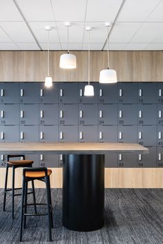 two stools sit in front of a long table with several lockers behind it