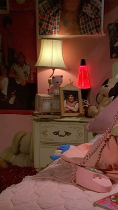 a bedroom with pink bedding and pictures on the wall above it, including a teddy bear