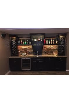 a home bar with wine bottles on the back wall and lights in the front area